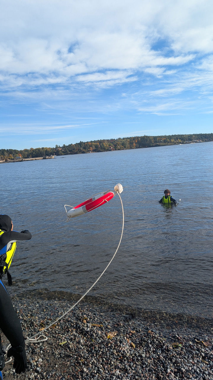 en person i en kajakk som holder en rød gjenstand i vannet