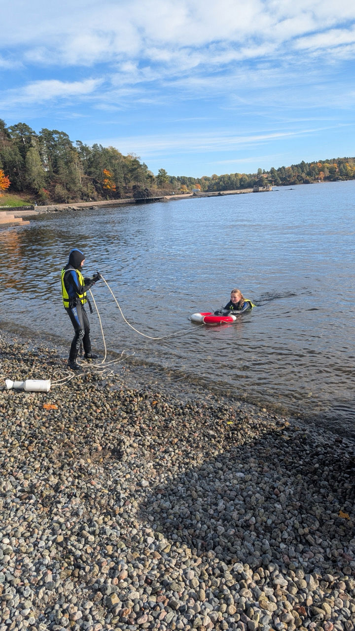 en person og en person på en steinete strand med en vannmasse bak seg