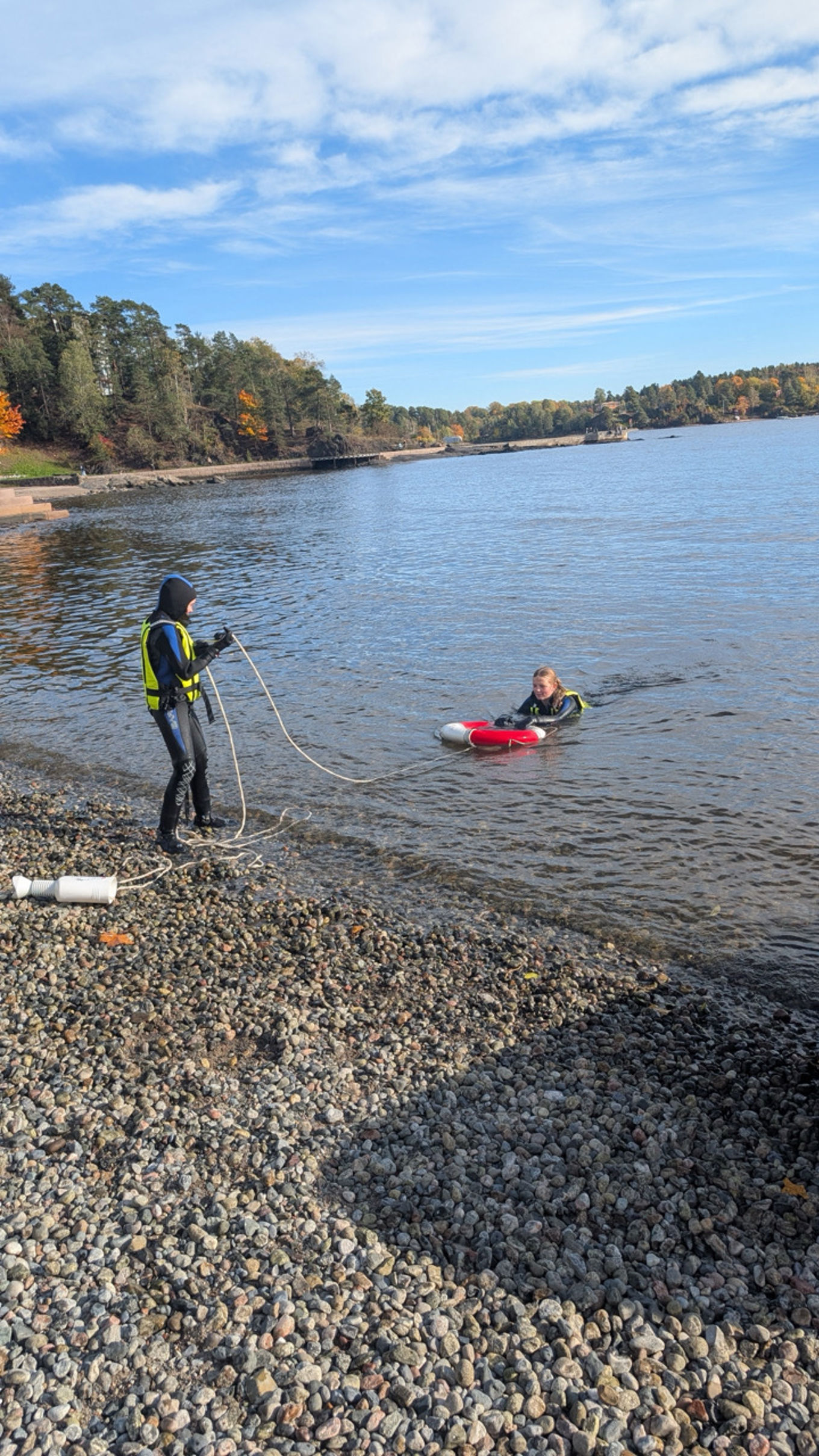 en person og en person på en steinete strand med en vannmasse bak seg