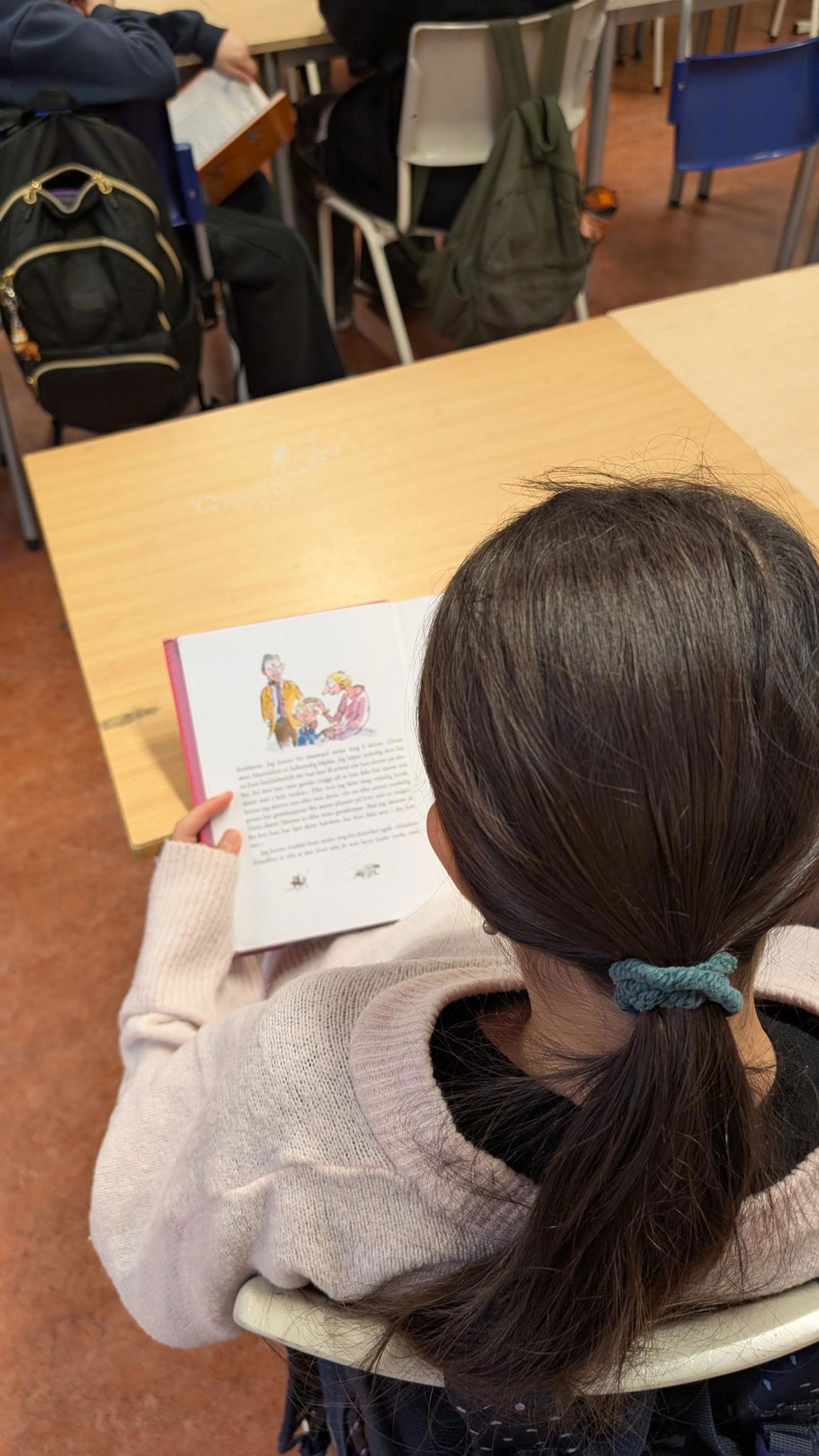 et barn som sitter ved et bord med et papir i hånden