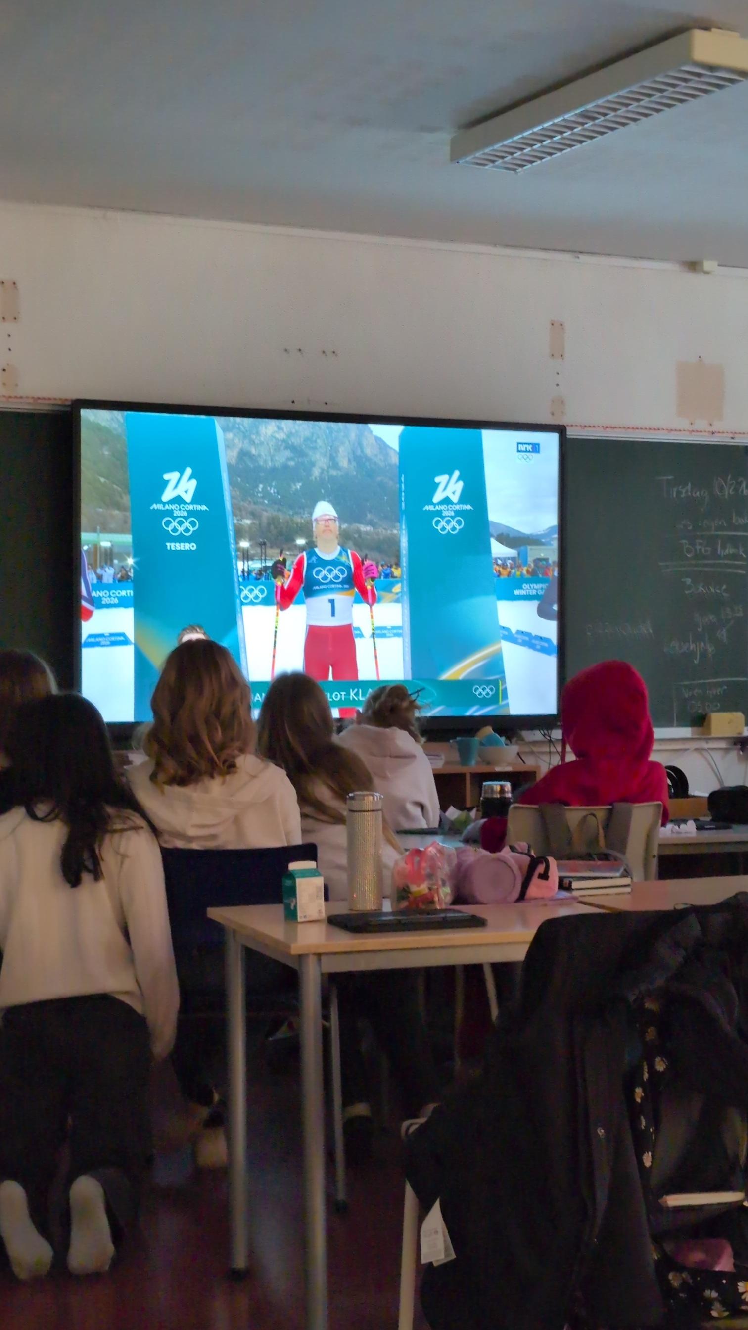 En gruppe mennesker som sitter ved et bord og ser på en skjerm